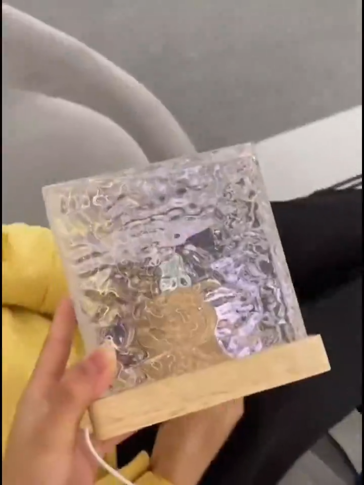 Cubo de cristal facetado sobre base de madera sostenido en la mano